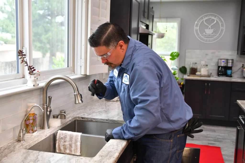 Professional inspecting a kitchen sink and plumbing in Albuquerque, NM