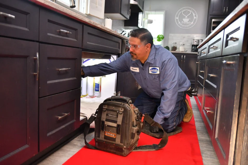 Professional plumber inspecting kitchen cabinet in Albuquerque, NM