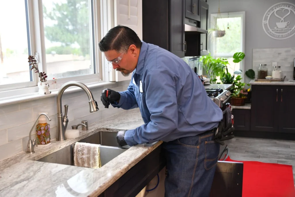 B. Carlson plumber inspecting kitchen sink plumbing during a filtration service in Albuquerque, NM