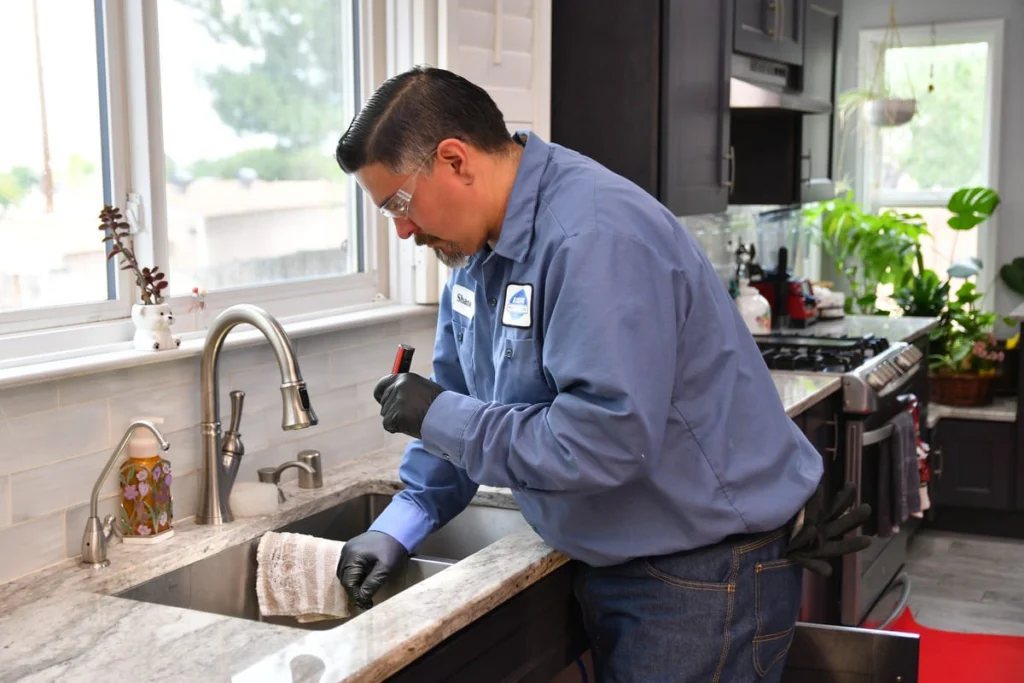 Plumber inspecting a kitchen sink during a water quality assessment in Albuquerque, NM