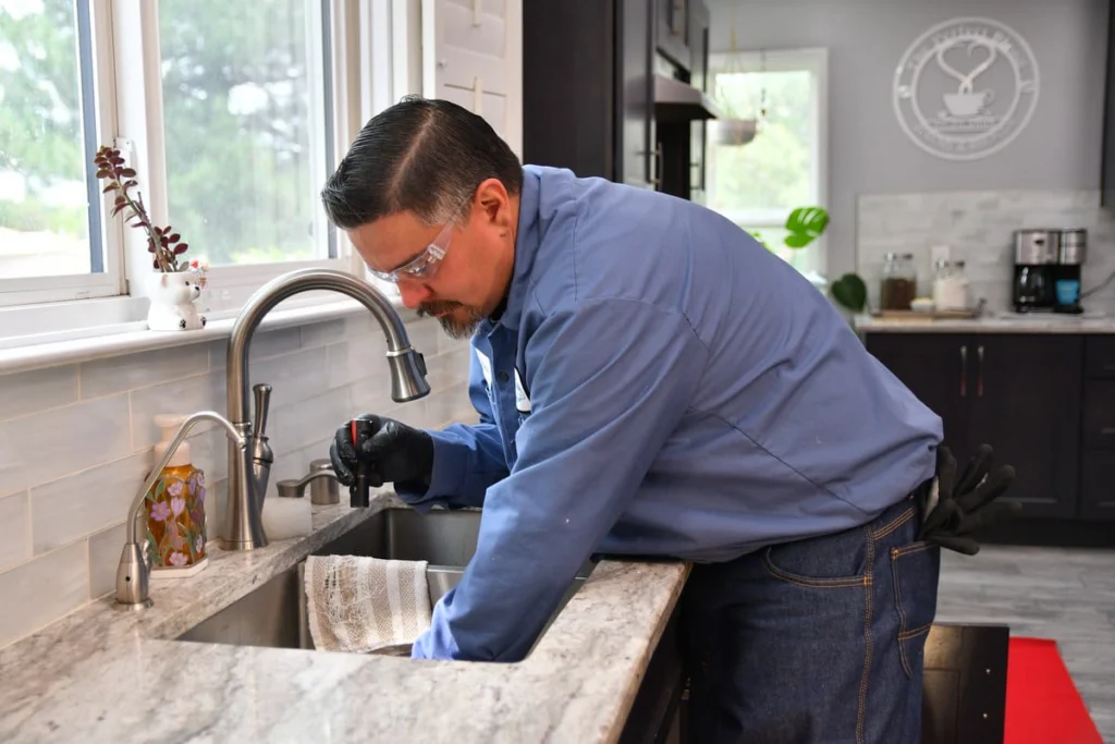 B. Carlson technician checking kitchen sink plumbing before installing water treatment equipment