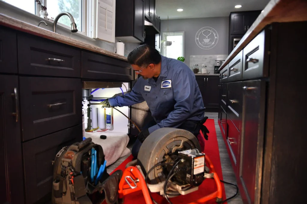 Technician running drain-clearing equipment at an Albuquerque home