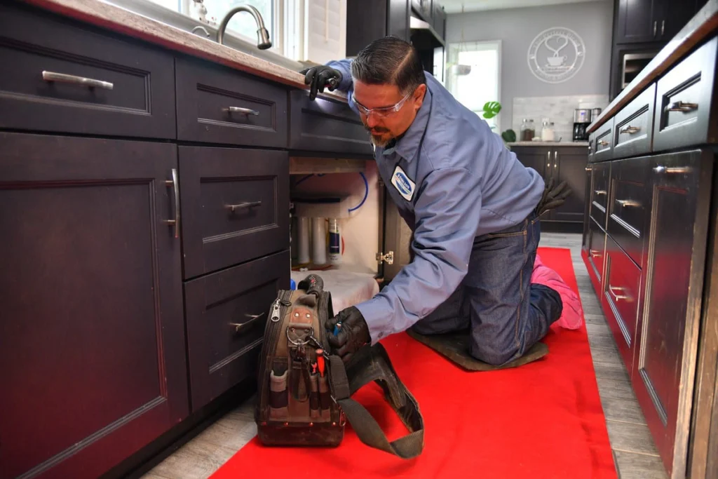 Professional plumber working under kitchen sink in Albuquerque, NM