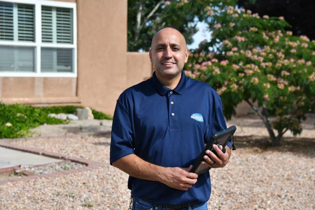 Technician with a tablet outside a residential building in Albuquerque, NM