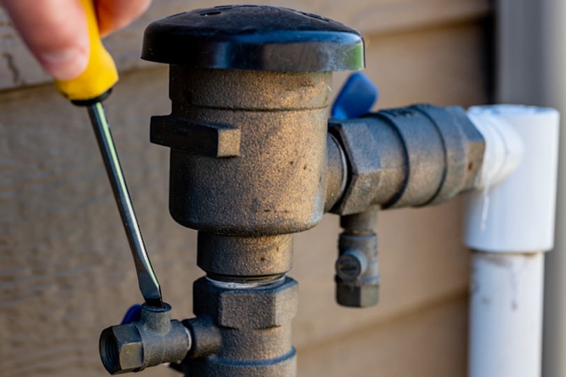 A tech tightening a screw on a backflow preventer