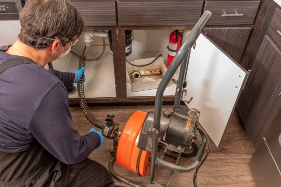 A plumber working with a machine to clear a drain.