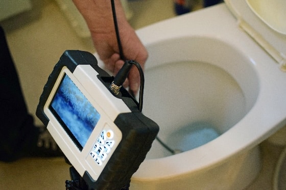 A tech using a camera to check out a clog in a toilet