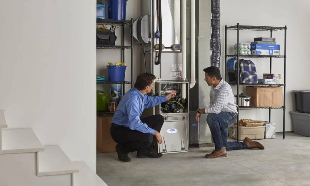 HVAC technician showing a home customer the insides of their gas furnace