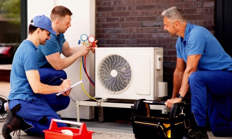 A group of a techs working on an outdoor HVAC unit.