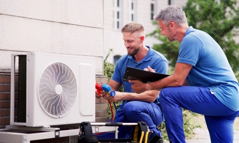 Two techs working on an outdoor HVAC unit.