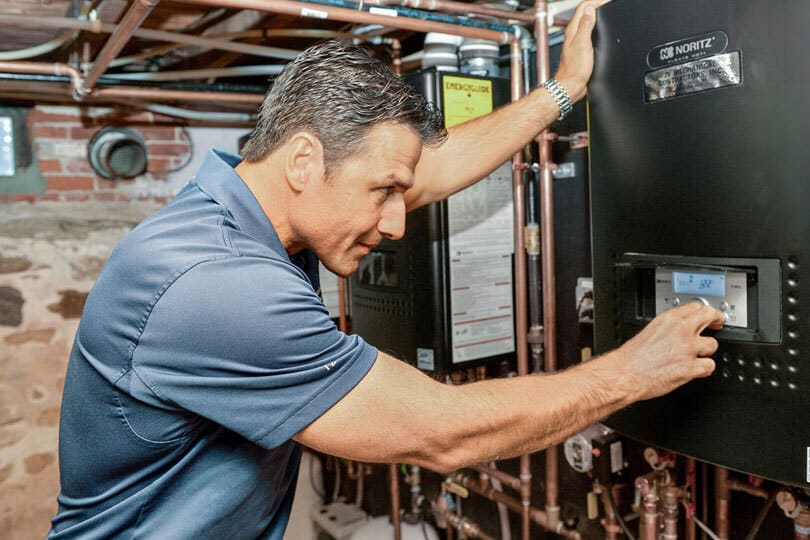 A plumber inspecting a tankless water heater