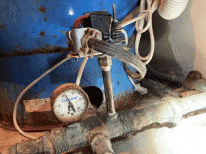 Old well pressure tank showing wear and low pressure gauge in Corrales home