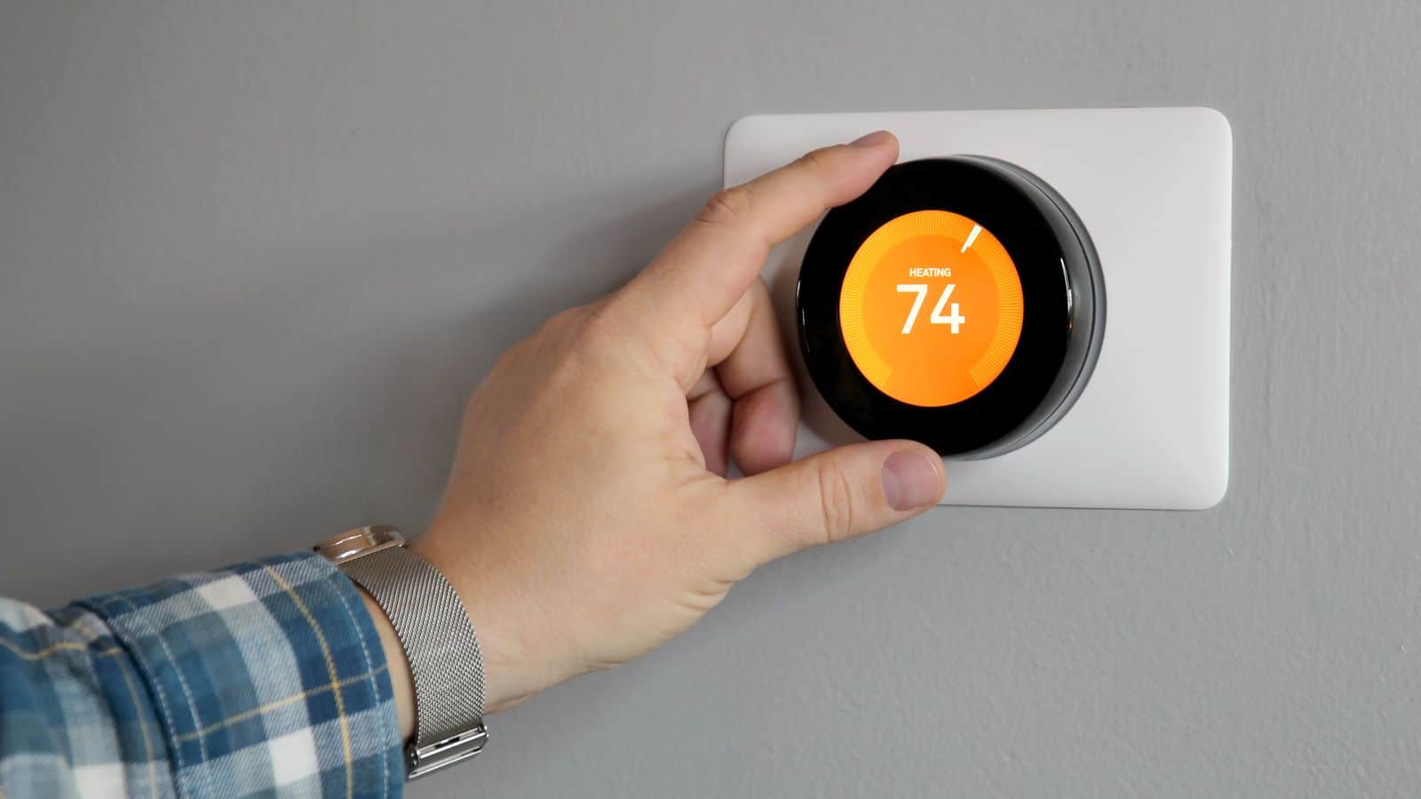 A person adjusting a smart thermostat